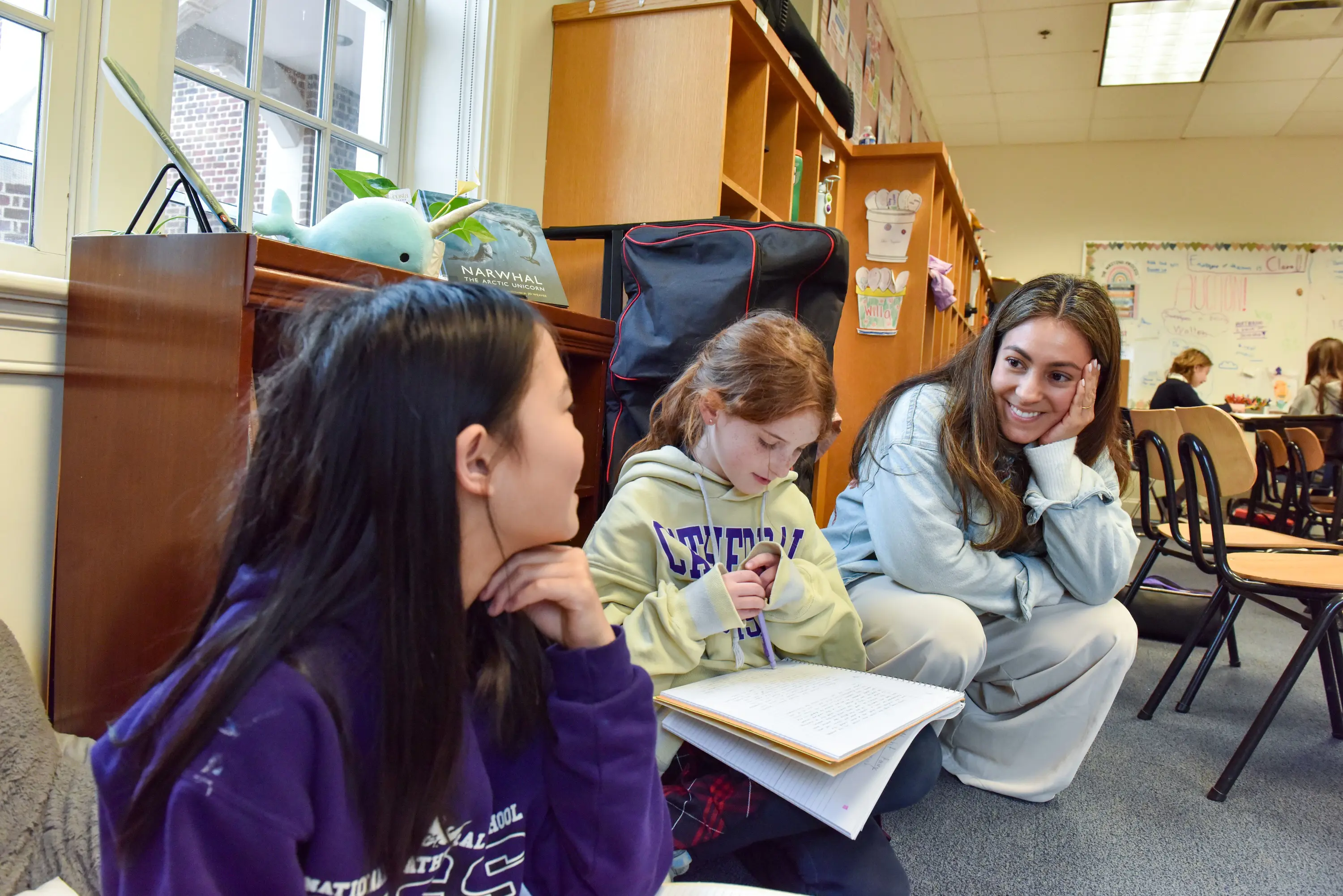 Teacher sitting with two younger NCS girls